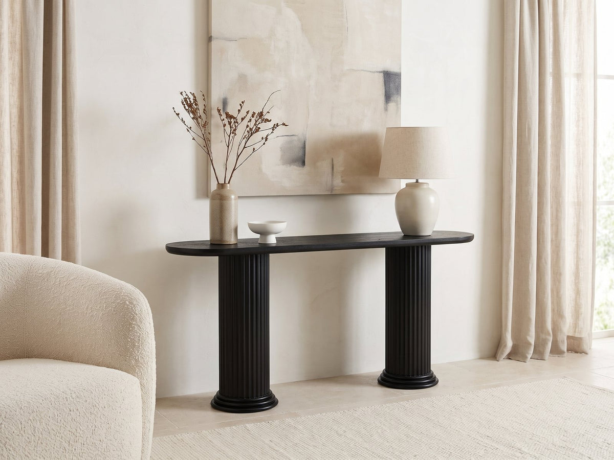 Imola Black Wood Veneer Oval Column Console Table against a plaster wall under an abstract canvas in a bright living room