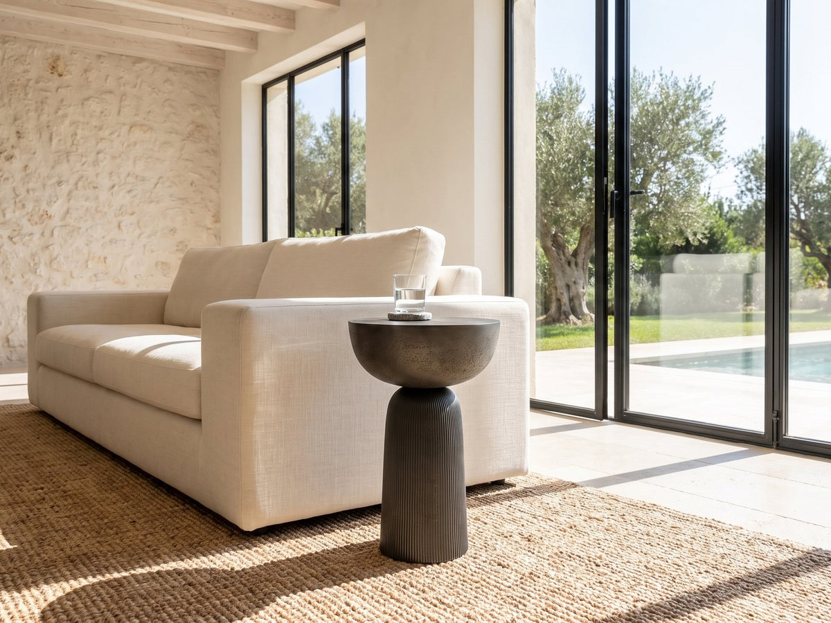 Irsina Cast Aluminum Tulip Pedestal Side Table beside a linen sofa in a poolside villa