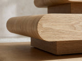 Close-up of the Ischia Natural Wood Veneer Stacking Coffee Table: the rounded veneer edge of a slab over its recessed plinth