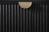 Close-up of the Isili nightstand: the fluted black drawer front with a half-moon pull in brushed antique brass