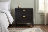 Isili black fluted nightstand against a pale sage green plaster wall in a Savannah bedroom with a dark heart pine floor