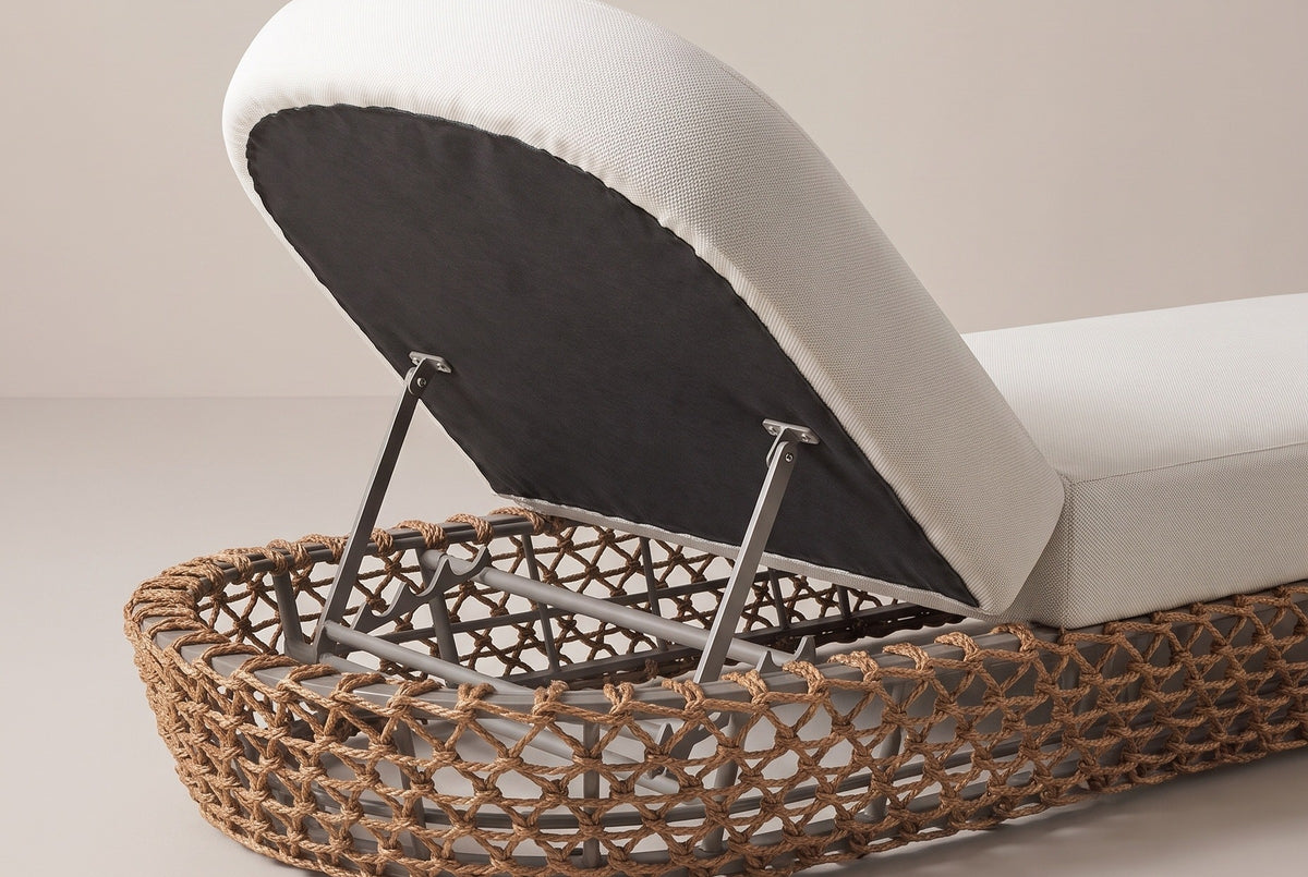 The head end of the Isnello lounger from behind: the raised backrest with its dark underside on two metal supports inside the woven base