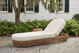 Isnello woven chaise lounger on grey bluestone in a Beaufort garden, a white clapboard wall with green shutters, ferns and a live oak with Spanish moss behind (stool and drink not included)