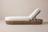 The Isnello lounger seen from the side: the long low woven base, the flat seat cushion and the raised backrest