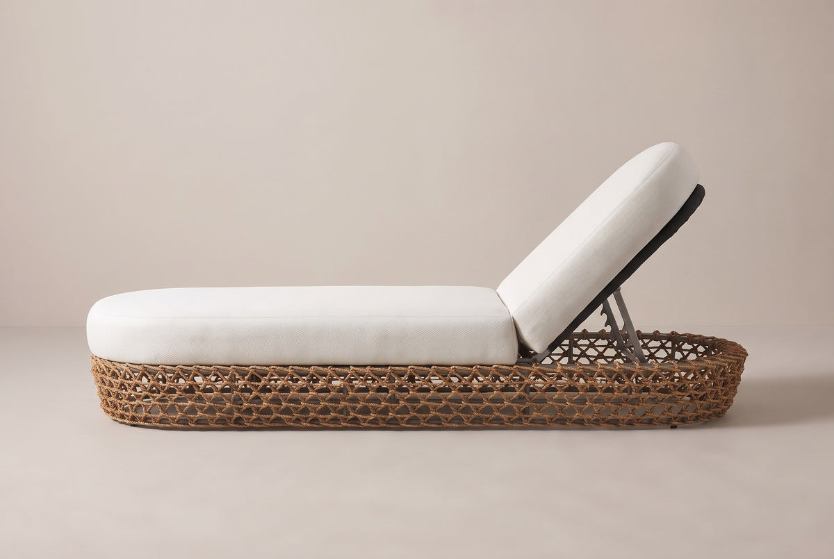 The Isnello lounger seen from the side: the long low woven base, the flat seat cushion and the raised backrest