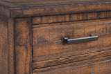 The corner of the framed top of the Ittiri nightstand with the wide front post, the top drawer front and one dark bronze bar pull on two small stepped posts
