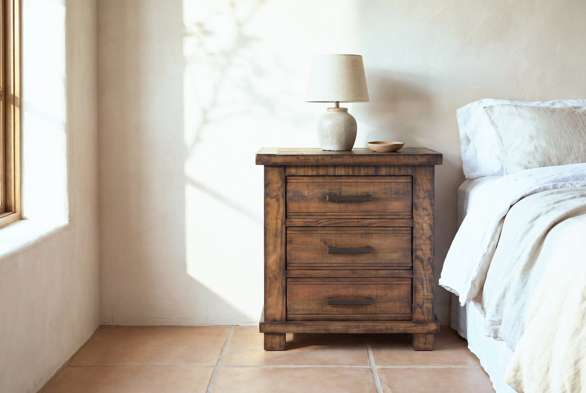 Ittiri reclaimed pine nightstand with a ceramic lamp beside a bed in a Santa Fe bedroom with pale sand limewash walls and terracotta floor tiles