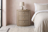 Jerzu cerused toffee oval nightstand with a ceramic lamp against a blush pink limewash wall in a Denver bedroom with grey-washed boards and a black steel window