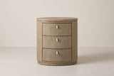 The Jerzu nightstand in cerused toffee, front view on a light studio backdrop: three bowed drawers with capsule pulls and a recessed oval plinth