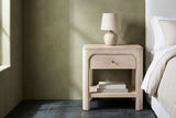 Laconi weathered mango arched nightstand with a ceramic lamp beside a bed in an Austin bedroom with an olive green limewash wall and a dark slate tile floor
