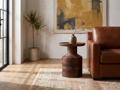 Lagonegro Solid Mango Pedestal Side Table with a stoneware vase beside a cognac leather armchair in a sunlit loft