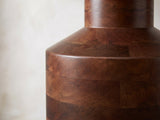 Close-up of the Lagonegro Solid Mango Pedestal Side Table: the neck and sloping shoulder over the stacked mango blocks