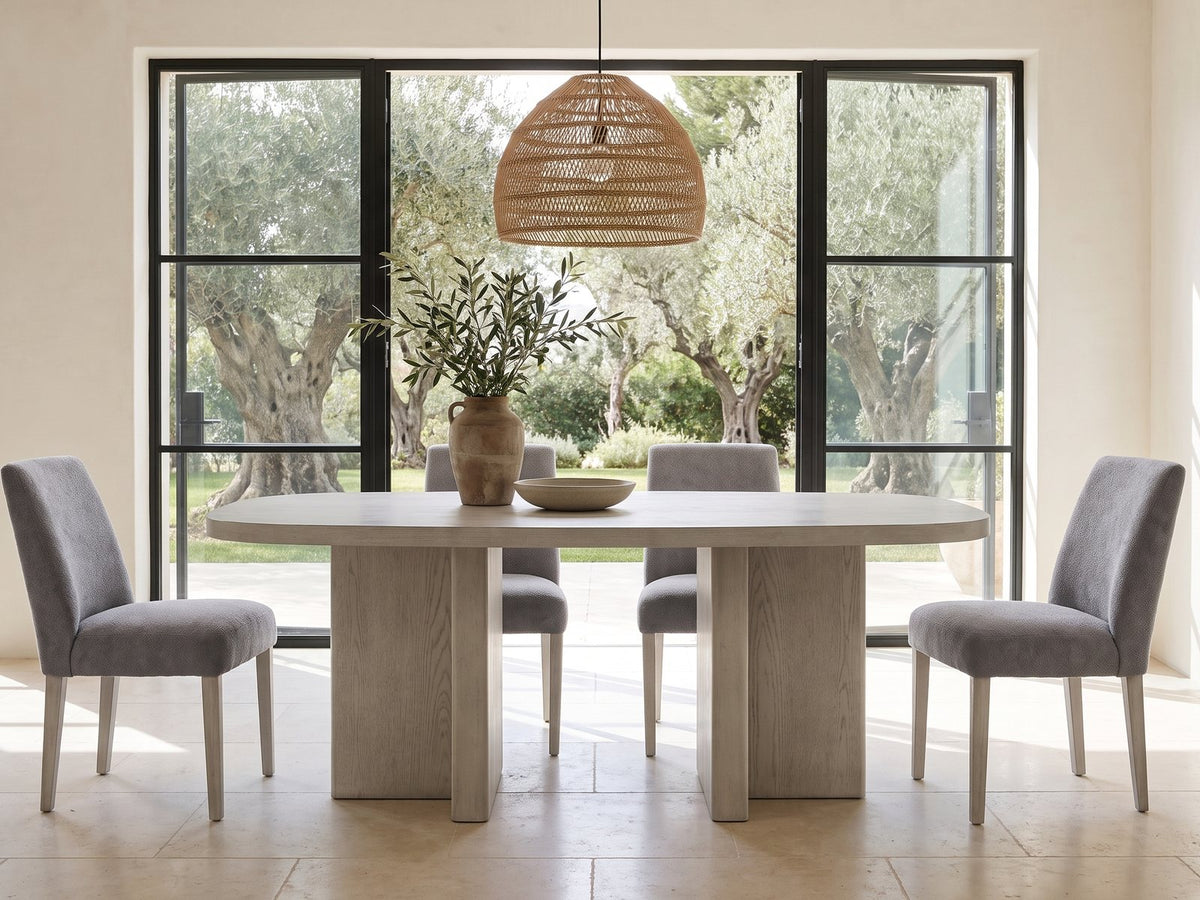 Laino 82-Inch Racetrack Oak Double Pedestal Dining Set with 4 Chairs in a sunlit villa dining area with olive trees outside