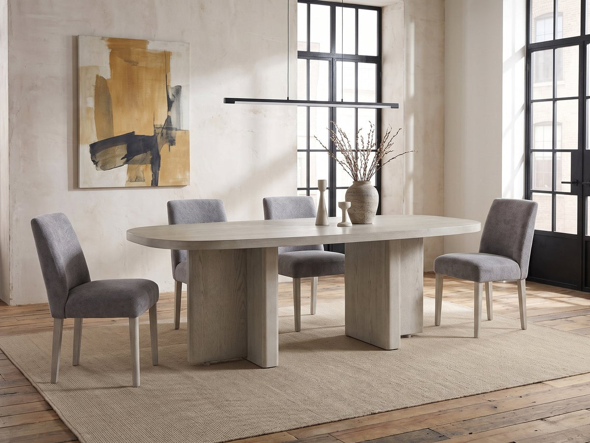 Laino 82-Inch Racetrack Oak Double Pedestal Dining Set with 4 Chairs in an industrial loft dining area