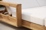 Close-up of the Lampedusa lounge: the solid acacia arm frame post and top rail with light natural grain, beside the cream cushion