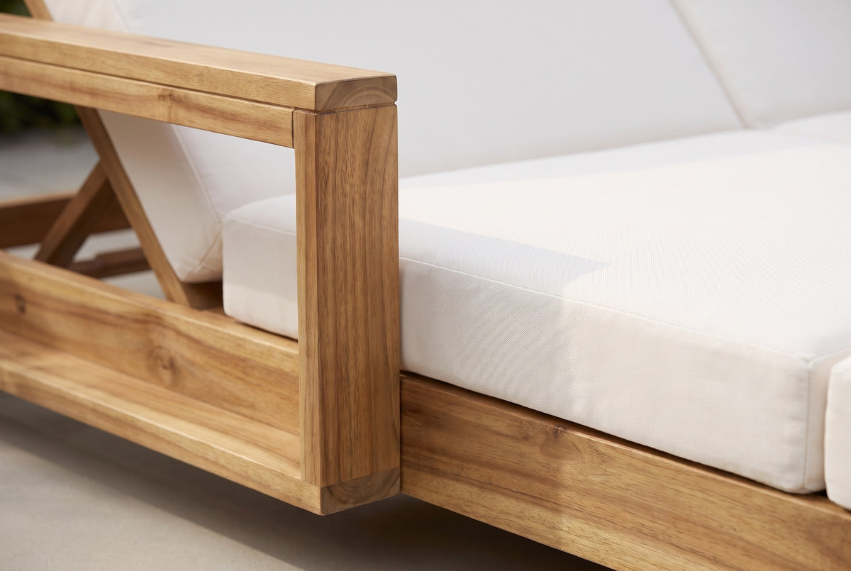 Close-up of the Lampedusa lounge: the solid acacia arm frame post and top rail with light natural grain, beside the cream cushion