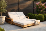 Lampedusa double chaise lounge on limestone pavers in a Houston garden at golden hour, a dark ipe fence, boxwood and a crape myrtle behind (planter and throw not included)