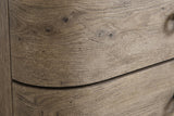 Close-up of the Lanusei nightstand: weathered English knotty oak veneer with small knots, open pores and a wavy grain, and the thin shadow line between two drawer fronts