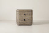 The Lanusei nightstand in weathered knotty oak, front view on a light studio backdrop: a thick top band, two drawers with black ring knobs, a bottom band and a recessed plinth