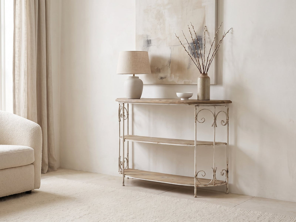 Latiano Fir and Scrolled Iron Three-Tier Console Table against a plaster wall under an abstract canvas beside a boucle armchair in a bright living room