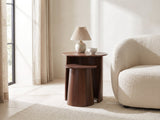 Laurenzana Dark Brown Mango Nesting Side Tables, Set of 2 with a lamp and a ceramic bowl beside a cream boucle armchair in a bright plaster room