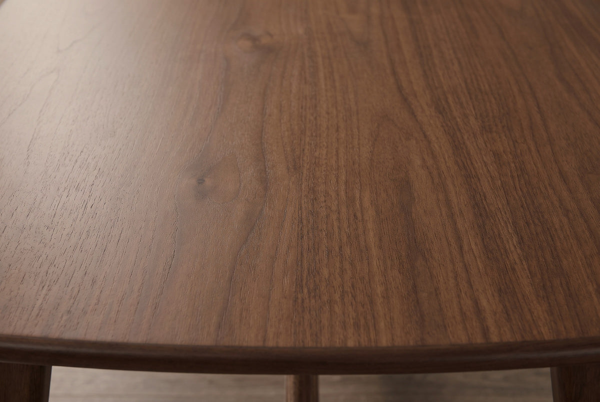 Close-up of the walnut veneer tabletop on the Lavello table: warm brown wood with fine grain running to a softly rolled edge