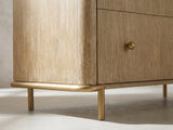 Close-up of the Lazise 38-Inch Sand Wash 5-Drawer Chest: the aged-brass metal sled under one end, the rod curving round the corner into a slim round leg