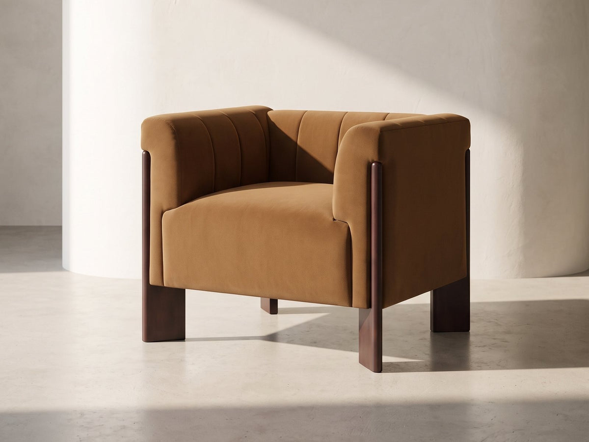 Lecce Channel Velvet Armchair in cognac against a plaster wall in morning light