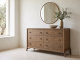 Lendinara 66-Inch Latte Elm 6-Drawer Dresser under a round bronze mirror in a villa bedroom