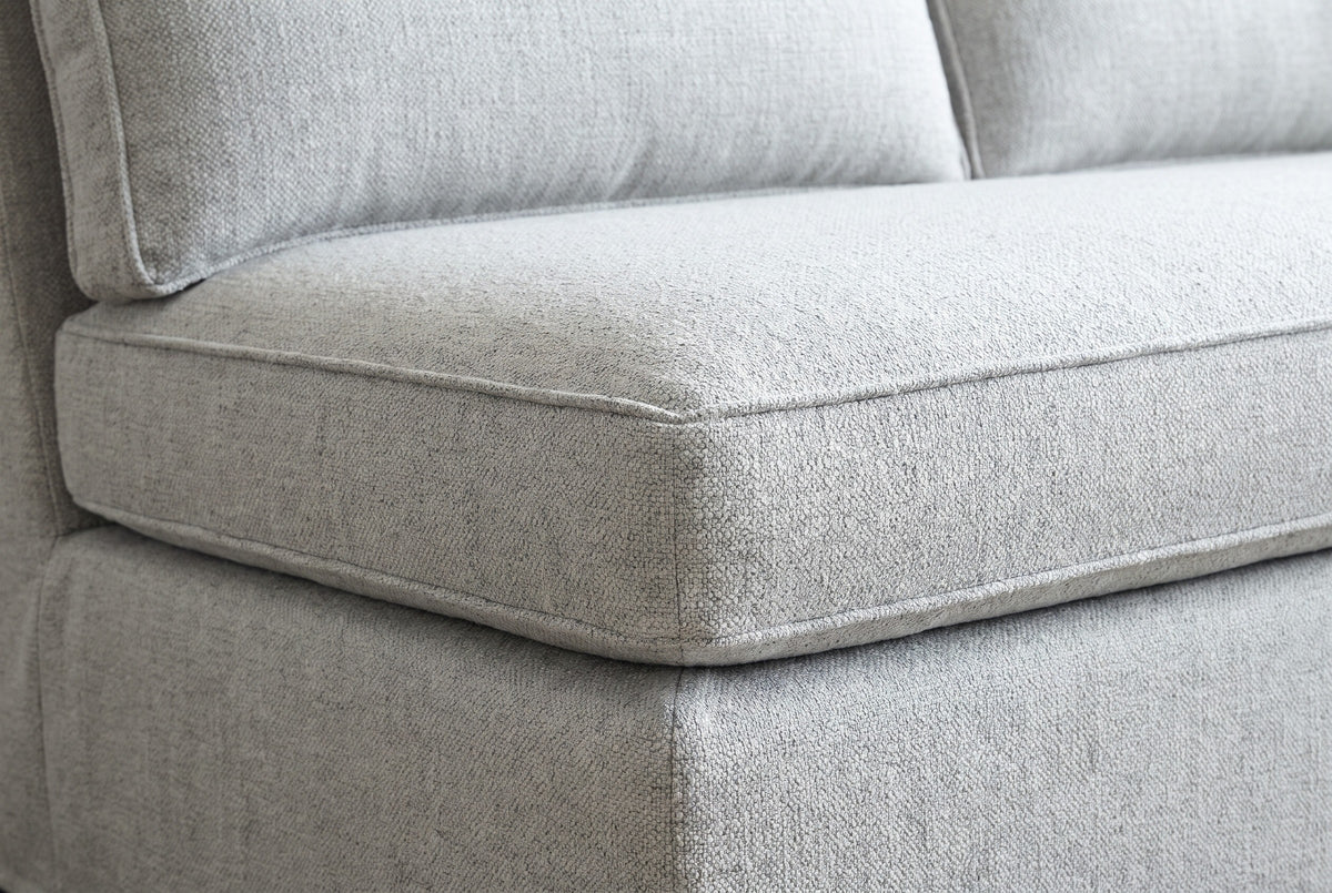 Close-up of the Lentini seat cushion corner: a nubby light grey weave, a self-piped seam and the edge of a flange pillow