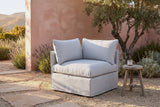 Lentini slipcovered corner chair in light grey in an Ojai hillside garden at golden hour, a terracotta-pink plaster wall and an olive tree behind (stool not included)