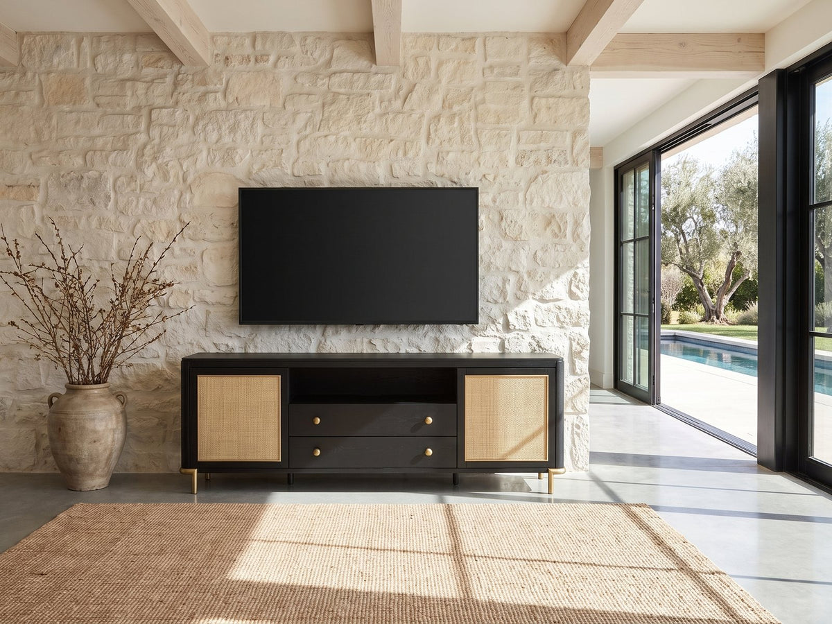 Levanto 80-Inch Black Ash and Rattan Media Console under a wall-mounted screen on a pale stone wall in a poolside villa