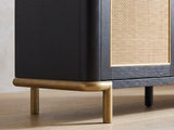 Close-up of the Levanto 80-Inch Black Ash and Rattan Media Console: the aged-brass sled base under the rounded end of the black ash case