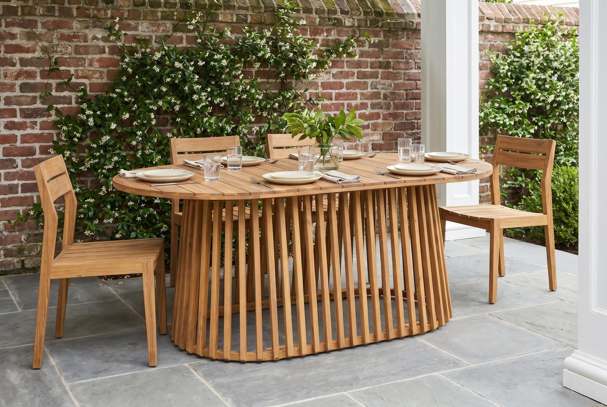 Levanzo oval acacia dining table in a Charleston garden loggia with an old red-brick wall, star jasmine and a bluestone floor (chairs and tableware not included)