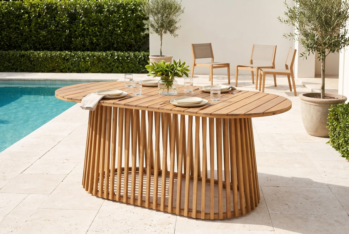 Levanzo oval acacia dining table on a limestone pool terrace at a Palm Beach villa, a clipped hedge and potted olive trees behind (chairs and tableware not included)
