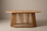 The Levanzo oval dining table seen from the long side: the slatted top above the flared slatted base