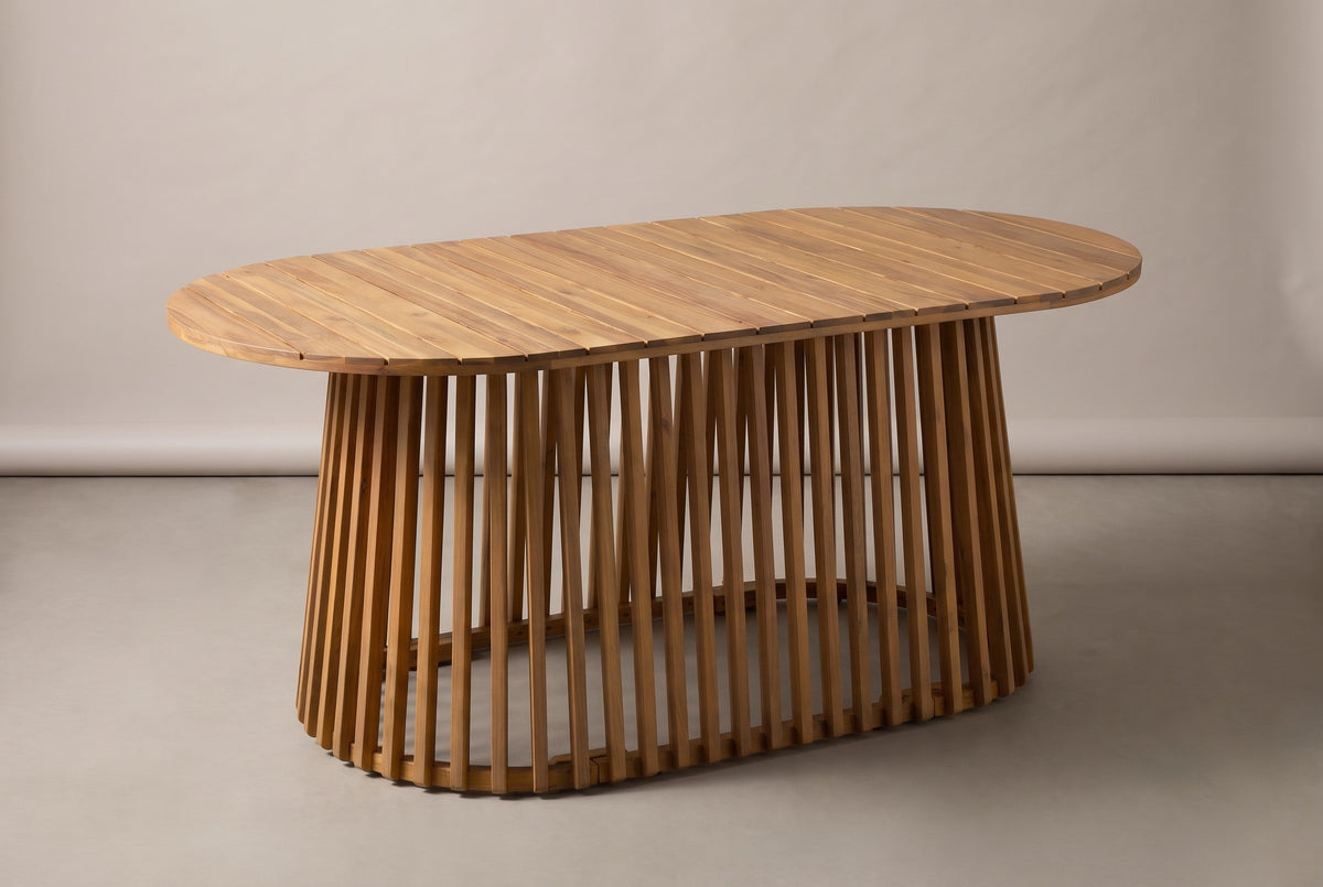 The Levanzo oval acacia dining table in light teak, three-quarter view on a light studio backdrop (sold without chairs)