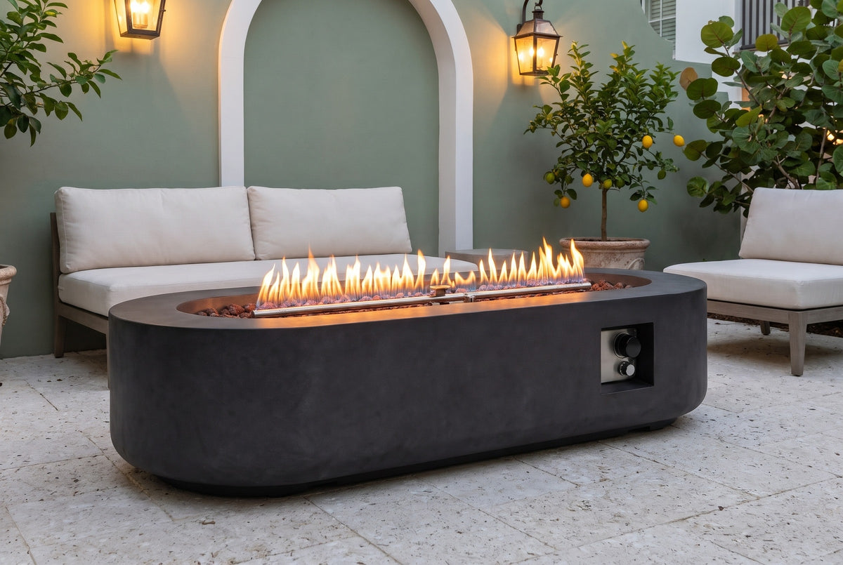 Licata fire pit table lit at dusk in a Rosemary Beach courtyard with a sage-green stucco wall, a white arch, lanterns and a potted lemon tree (sofa and chair not included)