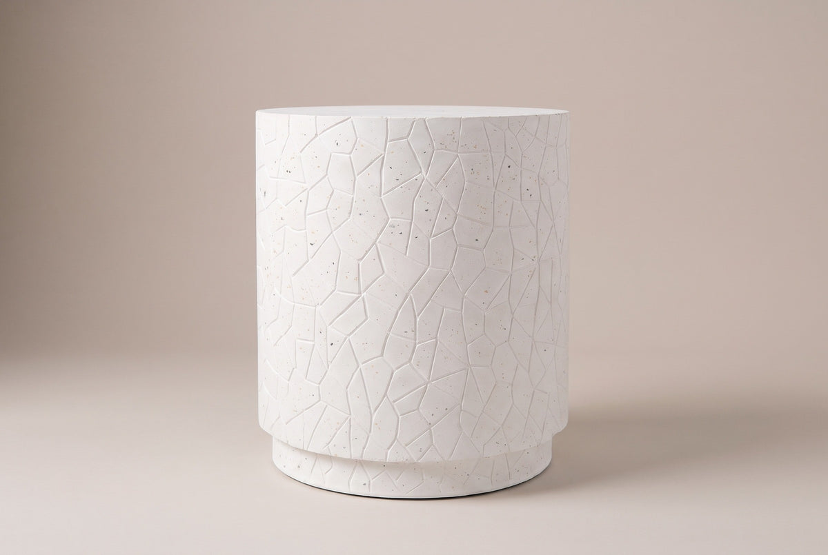 The Linguaglossa side table seen straight from the side: a straight white drum with raised crackle lines on a short recessed plinth