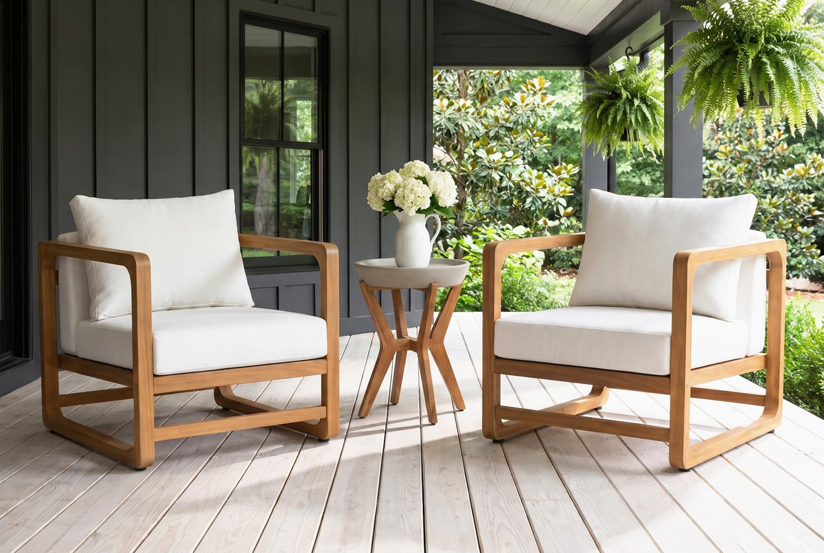 Linosa acacia lounge chairs and concrete side table on a covered back porch in Atlanta, Georgia, a charcoal board-and-batten wall, whitewashed floorboards and hanging ferns (jug and flowers not included)