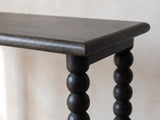 Close-up of the Lizzano Black Mango Wood Bobbin Console Table: the rounded top edge, the end rail and the ball-turned legs