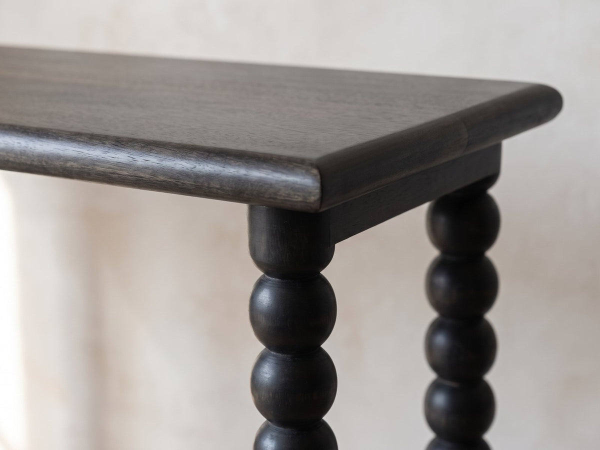 Close-up of the Lizzano Black Mango Wood Bobbin Console Table: the rounded top edge, the end rail and the ball-turned legs