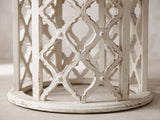 Close-up of the Locri 47-Inch Round Fir Lattice Pedestal Dining Table: the distressed antique-white lattice drum on its round plinth ring
