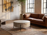 Lucignano Whitewashed Mango Drum Coffee Table on a vintage rug in front of a leather sofa in an industrial loft