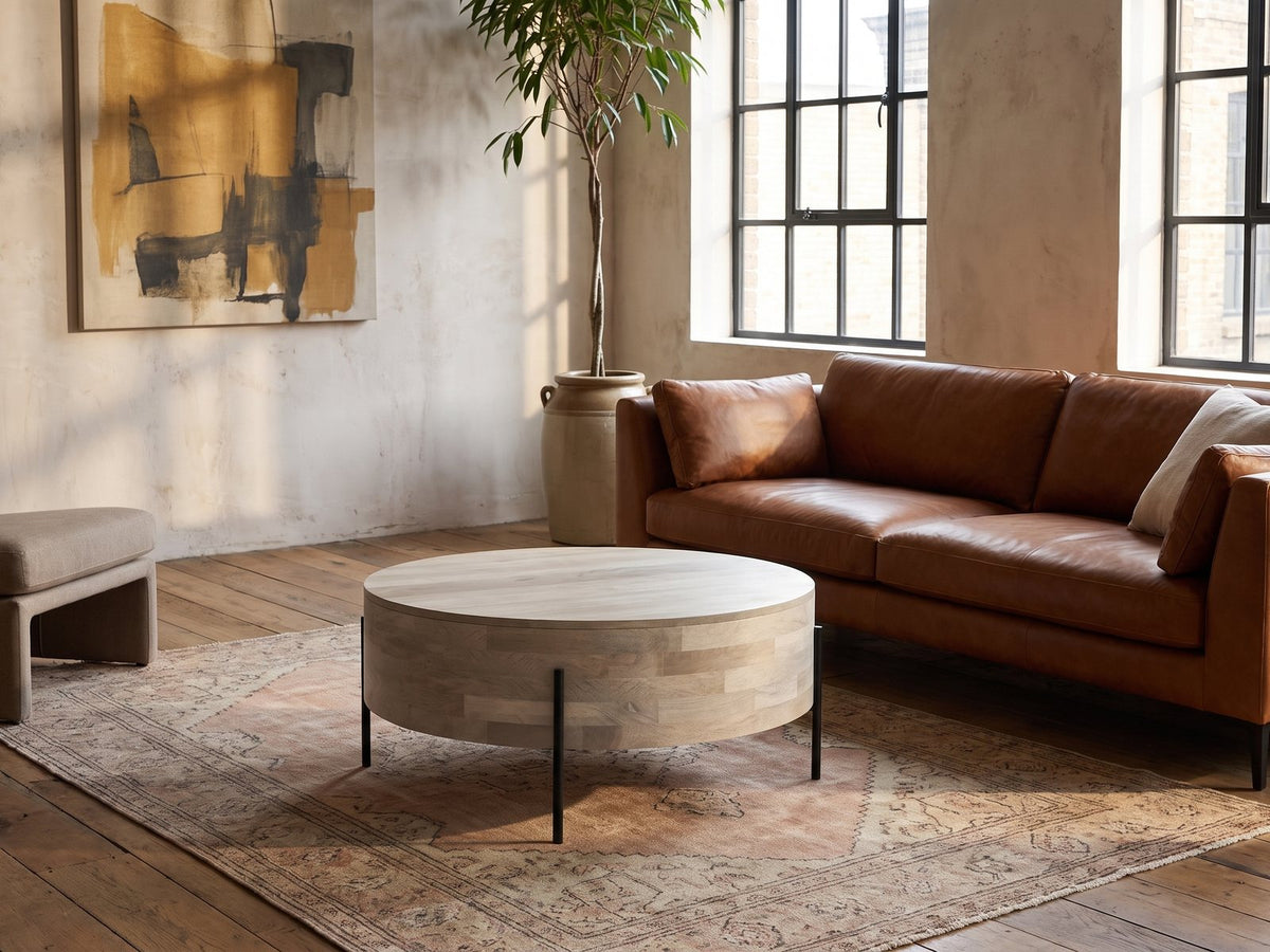 Lucignano Whitewashed Mango Drum Coffee Table on a vintage rug in front of a leather sofa in an industrial loft