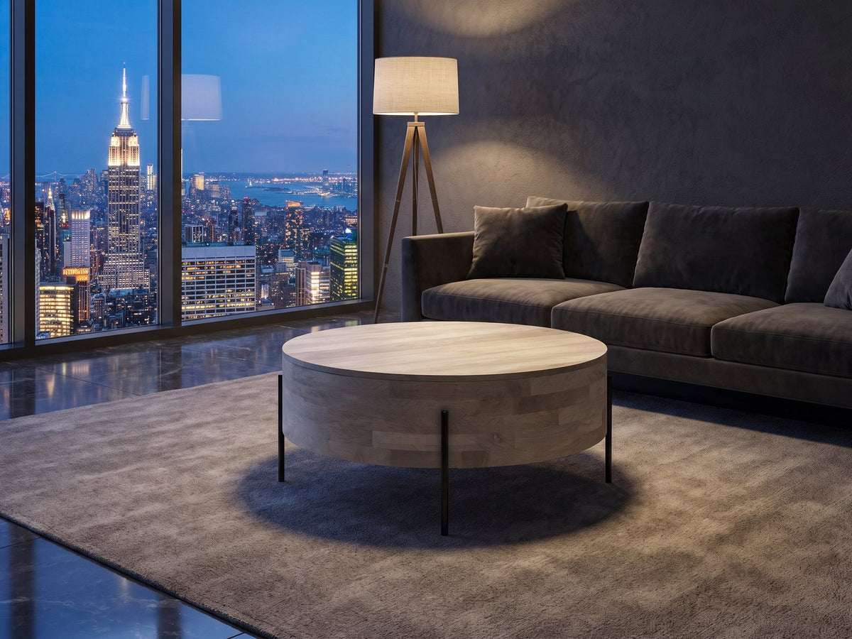 Lucignano Whitewashed Mango Drum Coffee Table on a wool rug in front of a velvet sofa in a city penthouse at blue hour