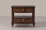 The Luras nightstand in dark cherry, front view on a warm studio backdrop: two bowed burl drawers with brass knobs, an open tier and shelf, and four brass-capped legs