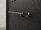 Close-up of the Lusiana 35-Inch Peppercorn Black 5-Drawer Chest: the wooden dowel pull held in antique-brass loops on the black peppercorn elm drawer front