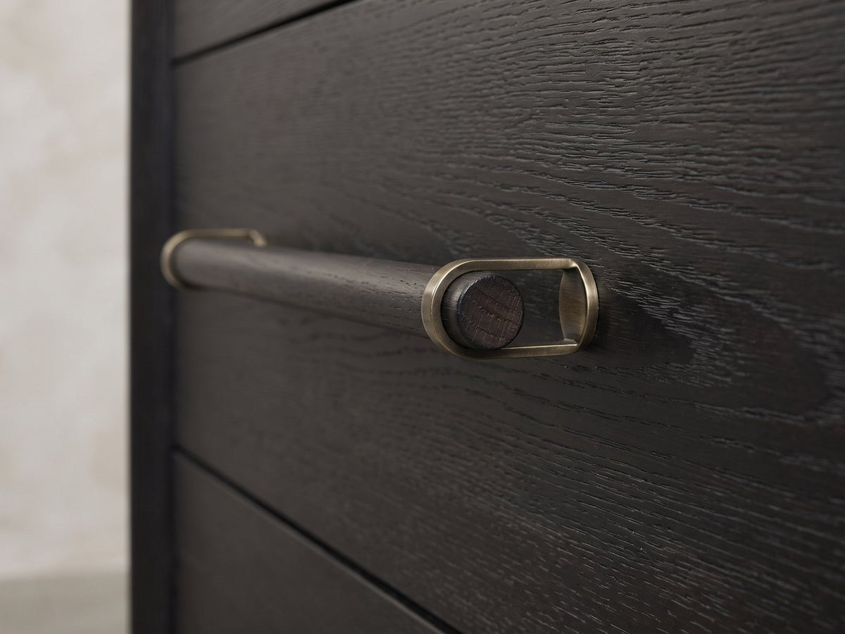 Close-up of the Lusiana 35-Inch Peppercorn Black 5-Drawer Chest: the wooden dowel pull held in antique-brass loops on the black peppercorn elm drawer front