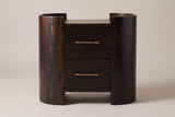 The Macomer nightstand in dark mocha mango, front view on a light studio backdrop: two half-round columns with the two drawers between them